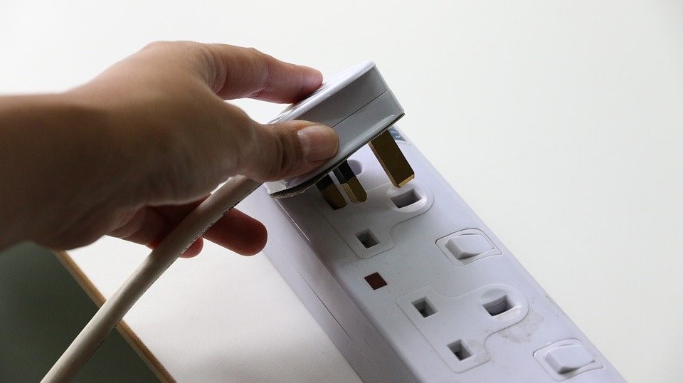 woman inserting plug in electrical socket